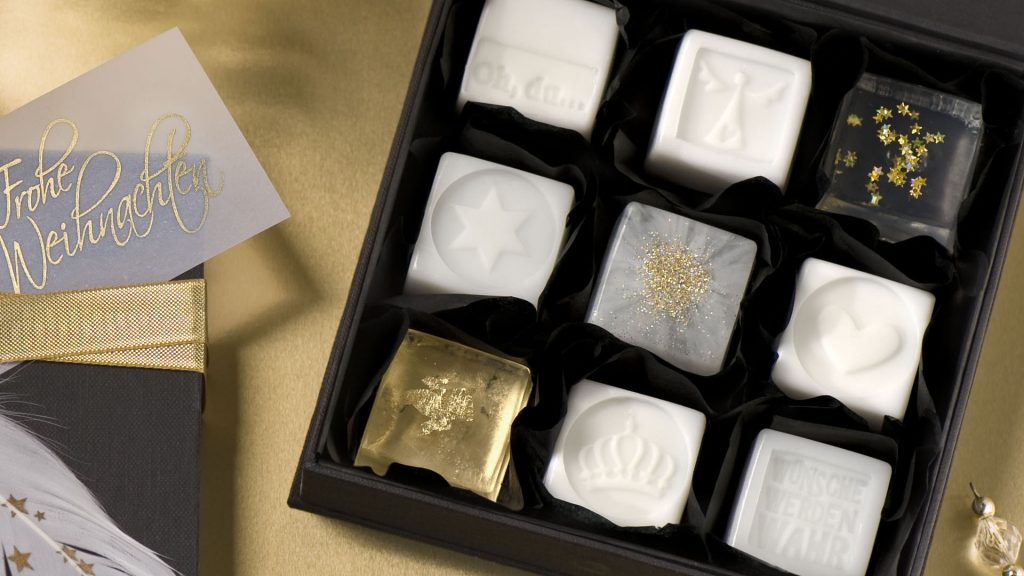 Ideen mit Seife für Weihnachten: Schmucke Stücke | Seifen als kleine Pralinen in Weiß und Transparent mit goldenen Sternen, Blattmetall in Gold und Flitter verziert